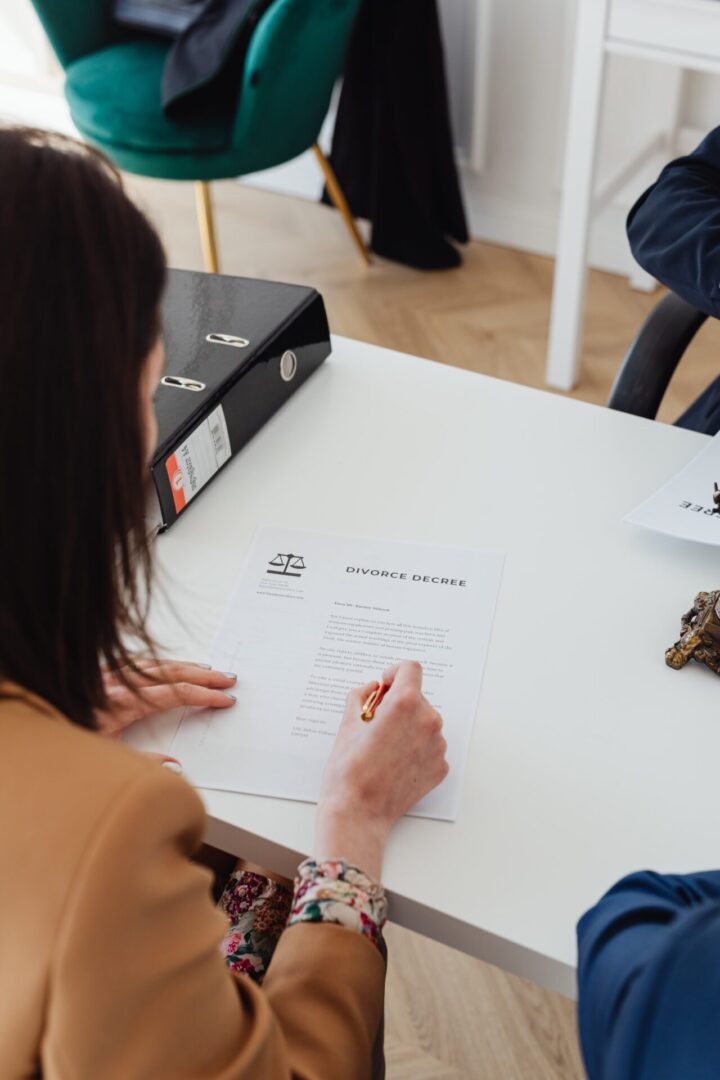 A woman is sitting at the table writing on paper.