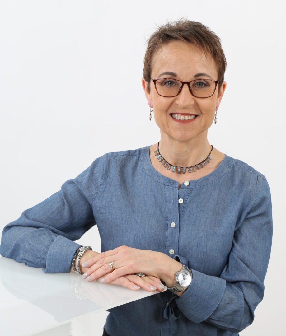 A woman sitting at a table with her hands on the desk.